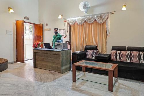 a man standing at a reception desk in a living room at OYO Flagship 87488 Hotel Green Breeze in Lohogaon