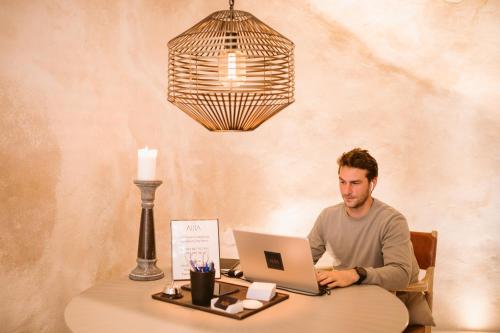 a man sitting at a table with a laptop computer at Casa Aura Hotel in Vejer de la Frontera