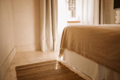 a bedroom with a bed and a window and a rug at Casa Aura Hotel in Vejer de la Frontera