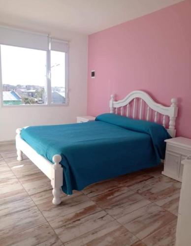 a bedroom with a bed with a blue blanket and a window at Depto para 4 personas in San Antonio Oeste