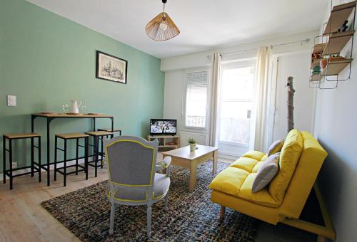 sala de estar con sofá amarillo y mesa en Appartement Cathédrale St Front, en Périgueux