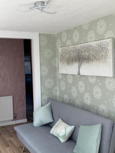 a living room with a couch and a painting on the wall at Hafan Traeth in Prestatyn