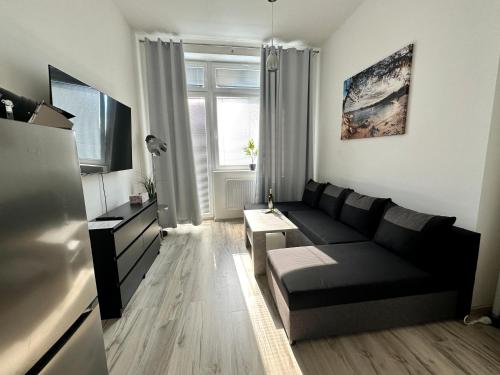 a living room with a black couch and a tv at Oskar Wilde in Stará Ľubovňa
