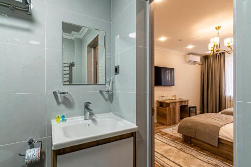 a bathroom with a sink and a bedroom at Oscar Hotel in Almaty