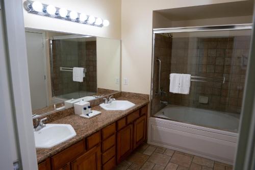 uma casa de banho com 2 lavatórios, uma banheira e um espelho. em Suites at Club De Soleil Las Vegas em Las Vegas