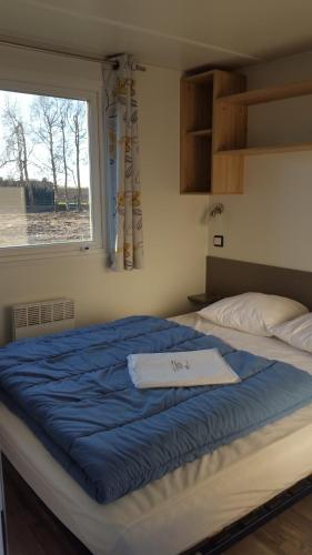 a bedroom with a large blue bed with a window at Camping La Berquerie in Le Mesnil-Réaume