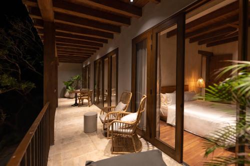 1 dormitorio con 1 cama y sillas en el balcón en Makani Luxury Wanderlust, en Tierra Bomba