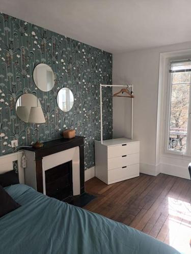 - une chambre avec un lit, une cheminée et un miroir dans l'établissement Très Parisien et ensoleillé, à Paris