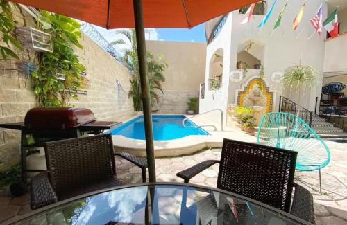 a patio with chairs and an umbrella and a pool at Suites Fenicia in Playa del Carmen