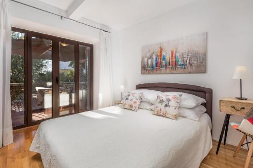 a white bedroom with a bed and a balcony at Apartments Carmen in Matulji