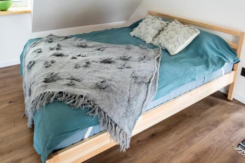 a bed with a blanket on top of it at Vakaras cozy apartment in the guest house with the terrace and the stunning view to the river side in Birštonas