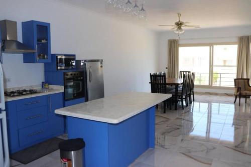 uma cozinha com armários azuis e uma mesa com cadeiras em Hacienda Bay 4 bedrooms Chalet em El Alamein
