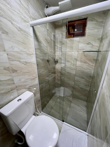 a bathroom with a toilet and a glass shower at Pousada Dona Felicidade Carneiros in Tamandaré