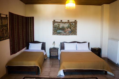 a bedroom with two beds and a painting on the wall at Varnous Hotel in Agios Germanos