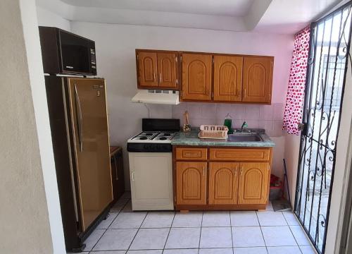 a small kitchen with wooden cabinets and a refrigerator at Casa El Amate in Emiliano Zapata