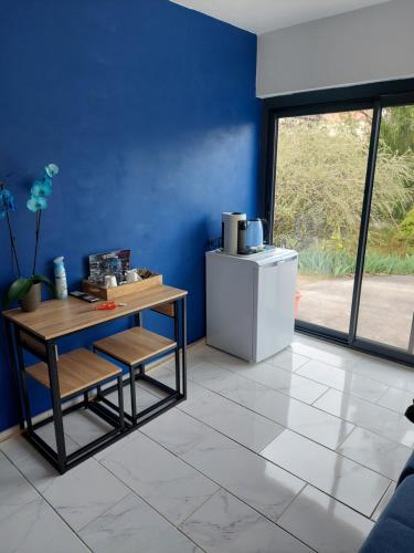 a blue room with a table and a refrigerator at L'hacienda de Maria montchanin in Montchanin