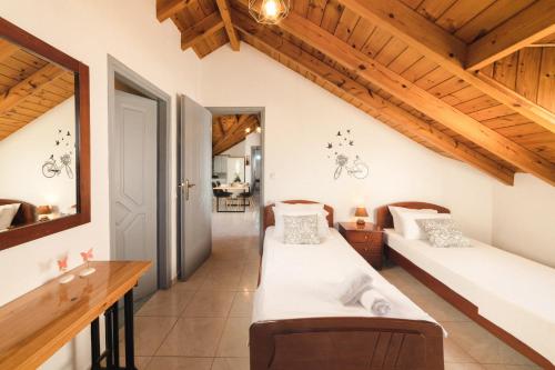 2 bedden in een kamer met houten plafonds bij George Beachfront Apartments in Lithakia