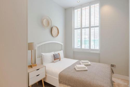 a white bedroom with a bed and a window at Central Holborn Bloomsbury flats in London