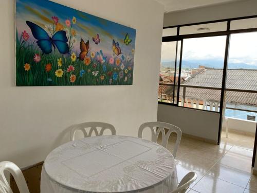 a dining room with a table and a painting of butterflies at Hotel Lina Maria in Tuluá