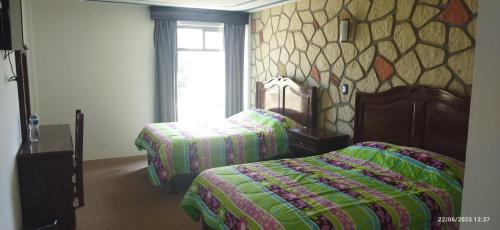 a bedroom with two beds and a stone wall at Hotel Sevilla Perote in Perote