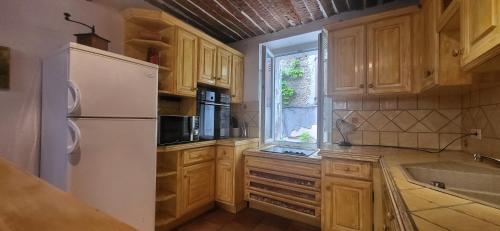 une cuisine avec des armoires en bois et un réfrigérateur blanc dans l'établissement Appartement centre village médiéval Bormes-les-Mimosas, 1 chambre, 3 personnes, à Bormes-les-Mimosas