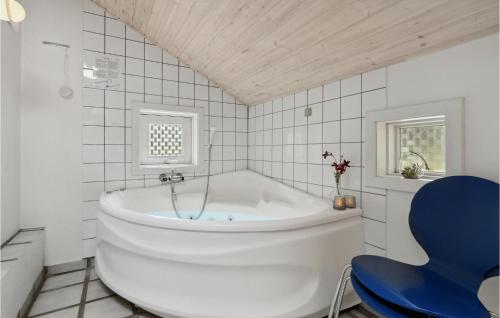 a white bathroom with a tub and a blue chair at Beautiful Home In Nex With Sauna in Vester Sømarken