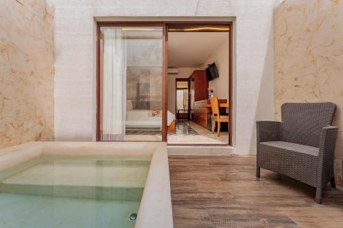 a room with a tub with a chair and a bedroom at Casona Las Tres Marías - Hotel Only adults in Mérida