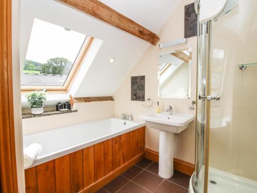 łazienka z umywalką, wanną i oknem w obiekcie The Olde Cowshed w mieście Acton Scott