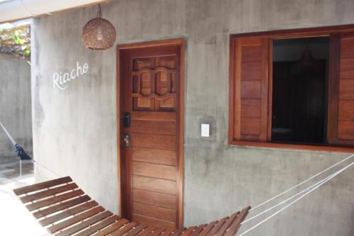 a porch with a hammock and a wooden door at Chalé Palhano Beach in São Miguel dos Milagres