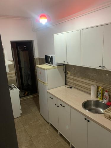 - une cuisine avec des placards blancs et un évier dans l'établissement The View Apartment, à Constanţa
