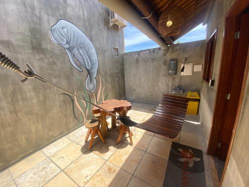 a room with a table and a bench and a wall at Chalé Palhano Beach in São Miguel dos Milagres