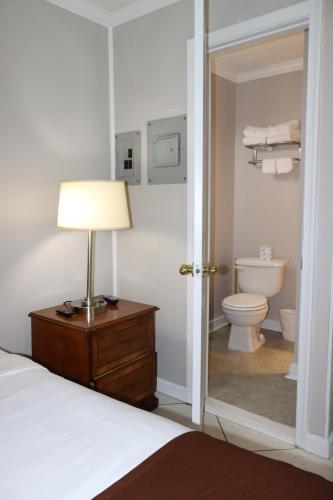 1 dormitorio con cama, lámpara y aseo en The Burgundy Inn Hotel and Apartments, en Ocean City