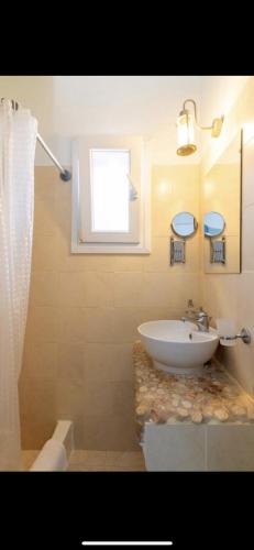 a bathroom with a white sink and a window at Studios Eleni II in Tinos Town