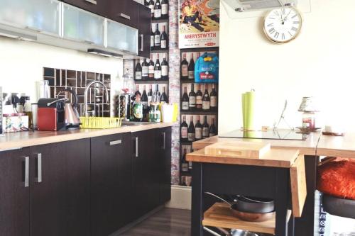 a kitchen with black cabinets and a wall of wine bottles at Sunny View in Aberystwyth