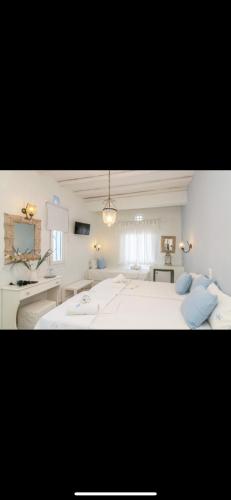 a bedroom with a large white bed with blue pillows at Studios Eleni II in Tinos Town