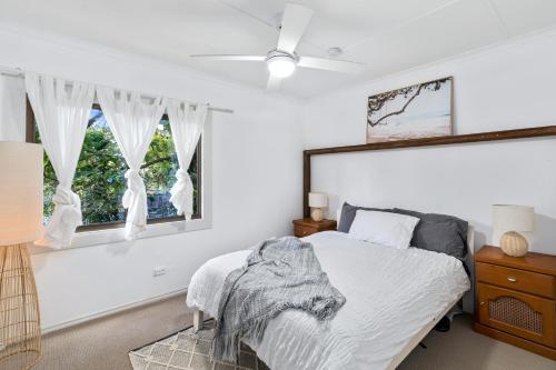 a white bedroom with a bed and a window at Secluded Waterfront House on Rainforest Acerage in Wisemans Ferry
