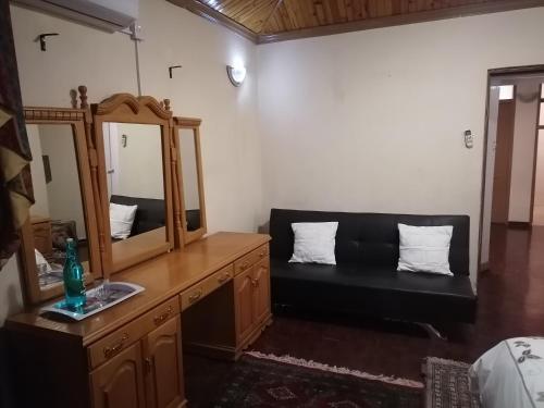 a vanity with a mirror and a couch in a room at Tjibelu's Nest Guest Home in Lobatse