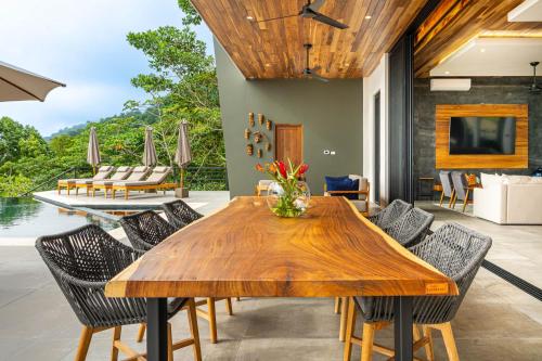 a dining room with a wooden table and chairs at Casa Amigos - By Pura Villas in Dominical