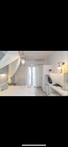 a white room with a bed and a window at Studios Eleni II in Tinos