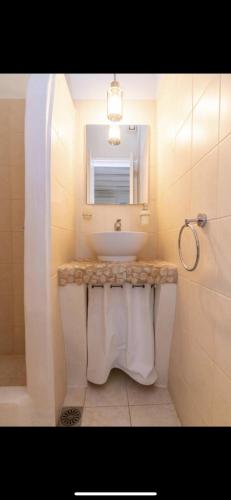 a white bathroom with a sink and a mirror at Studios Eleni II in Tinos Town