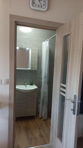 ein Badezimmer mit einem Waschbecken, einer Dusche und einer Uhr in der Unterkunft Bicik-Lak in Balatonfůzfő