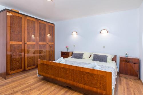 a bedroom with a large bed with wooden cabinets at Charming holiday house with beautiful garden and grill in Loborika