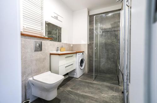 y baño con aseo, ducha y lavadora. en Widok na Morze Apartament przy plaży Premium by STAYLY, en Dziwnów