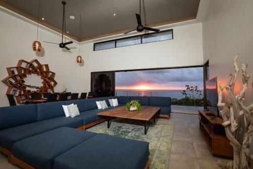Una sala de estar con un sofá azul y una mesa. en Casa Ola Vista - by Pura Villas, en Dominicalito
