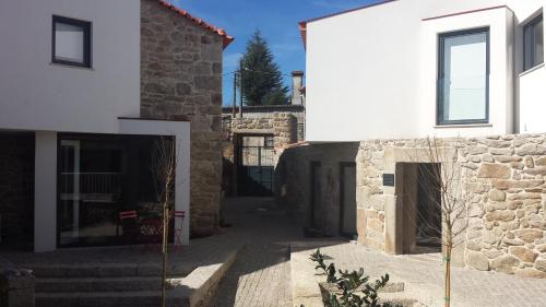 a white building with a doorway and a stone wall at Casas de Campo da Barroca in Tabosa