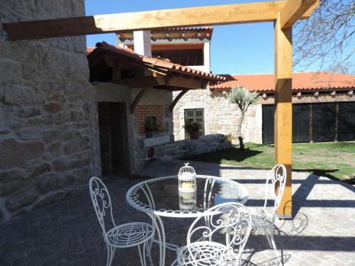 a patio with a table and chairs and a building at Casas de Campo da Barroca in Tabosa