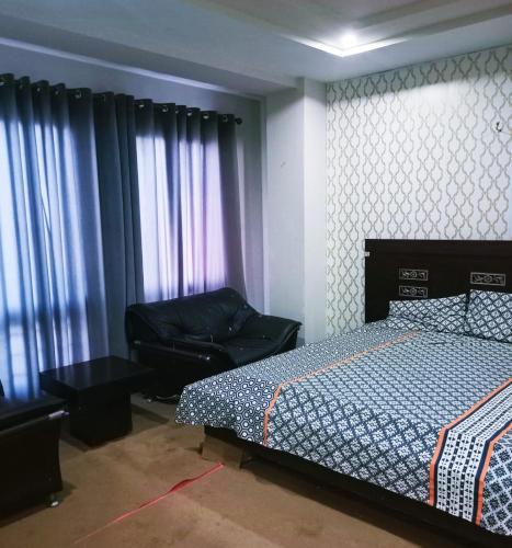 een slaapkamer met een bed, een bank en ramen bij Bahria town islamabad in Rawalpindi