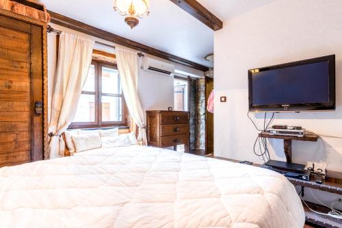 a bedroom with a large bed and a flat screen tv at Stone House Srida in Baška Voda