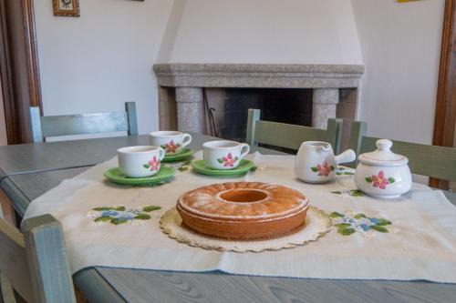 a table with a cake and cups and a fireplace at NONNU NONNA in Padru