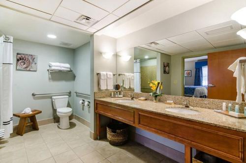 y baño con 2 lavabos, aseo y espejo. en Unity Hotel and Conference Ctr, Ascend Hotel Collection, en Kansas City